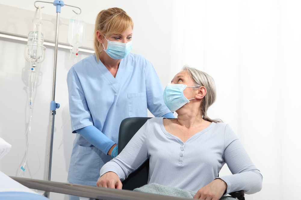 Medical assistant wearing mask helping a patient