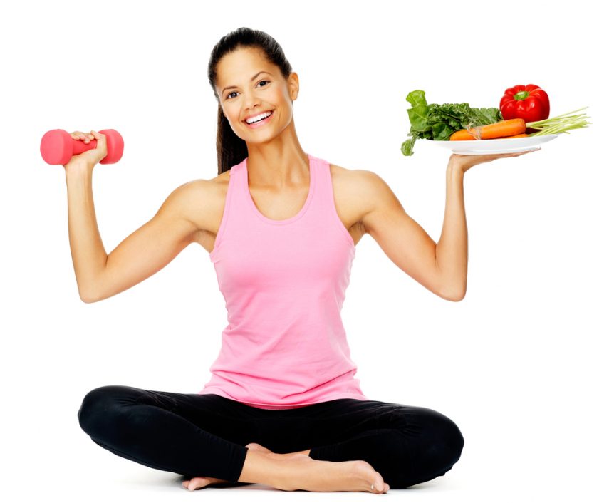 Healthy woman holding a hand weight and plate of vegetables