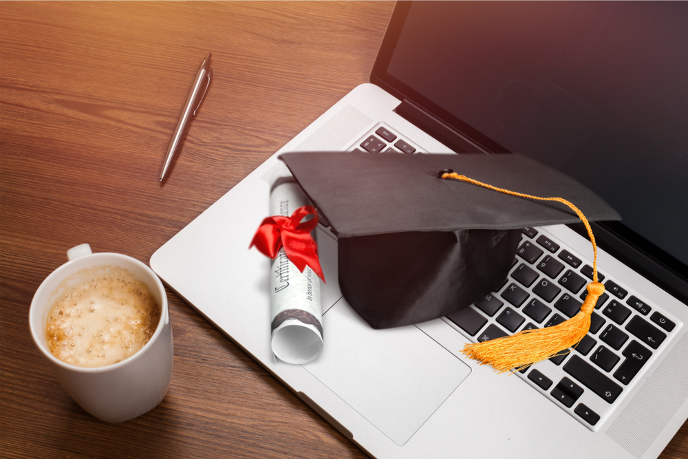 Graduation cap and diploma sitting on laptop