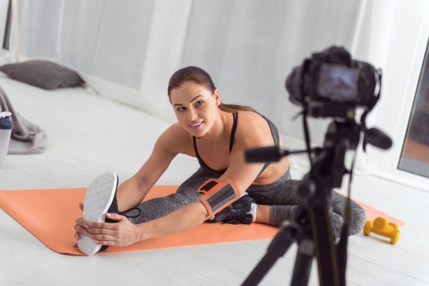 Sporty Woman Stretching on a Mat and Making a Workout Video