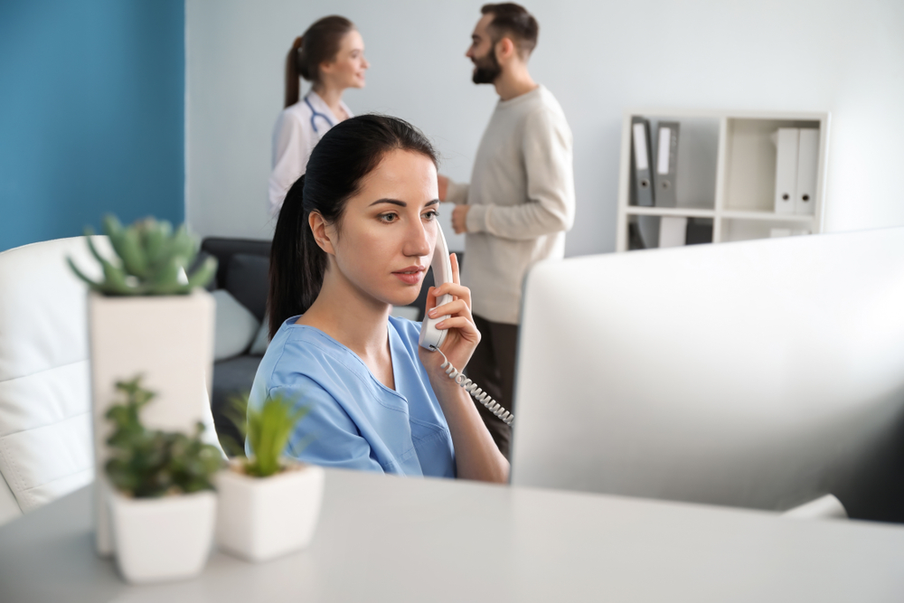 Medical Assistant talking on the phone in front of a computer